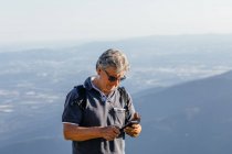 Старший использует свой мобильный телефон в горах — стоковое фото