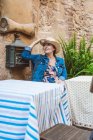 Donna in paglia cappello e vestito seduto sulla terrazza del ristorante nella città medievale — Foto stock