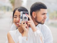 Junges Paar sitzt auf Holzbank und hat Spaß beim Fotografieren — Stockfoto