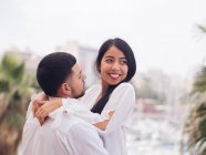 Side view of lovely young couple in light clothes bonding and hugging with love and tenderness on dock in port — Stock Photo