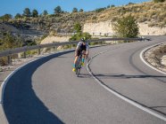 Homme en bonne santé à vélo sur la route de montagne dans la journée ensoleillée — Photo de stock