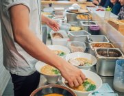 Вид збоку людини покласти нарізаний м'яса в миску японської страви в азіатському ресторані — стокове фото