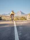 Homem saudável andar de bicicleta na estrada da montanha em dia ensolarado — Fotografia de Stock