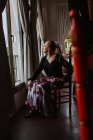 Приваблива вдумлива жіноча танцівниця в квітковій спідниці для фламенко, що сидить і дивиться у вікно — стокове фото