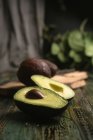 Ganze und halbierte frische Avocados auf rustikalem Holztisch — Stockfoto