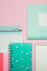 Композиція барвистих блокнотів і ручки, розташованих на рожевому столі — стокове фото