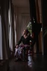 Attraente ballerina pensierosa in gonna floreale per flamenco seduta e guardando fuori dalla finestra — Foto stock