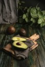 Abacates frescos inteiros e cortados pela metade na mesa de madeira rústica — Fotografia de Stock