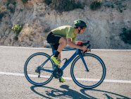 Primo piano di uomo sano in sella alla bicicletta sulla strada di montagna nella giornata di sole — Foto stock