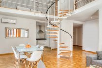 Інтер'єр стильної їдальні і сходів у великій сучасній дворівневій квартирі в денному світлі — стокове фото