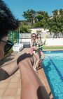 Друзья играют с водяными пистолетами в бассейне в солнечный летний день — стоковое фото
