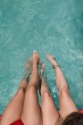 Cultivo lesbianas pareja sentado en piscina - foto de stock