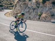 Uomo sano in bicicletta sulla strada di montagna nella giornata di sole — Foto stock