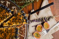 Appetizing fragrant passion fruit pie with blueberry topping decorated with bunch of lavender with slice on spatula — Stock Photo