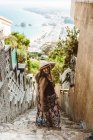 Жінка в літньому вбранні, стоячи на вулиці кам'яні сходи з морським узбережжям на фоні — стокове фото