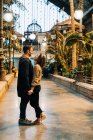 Веселые юноша и девушка обнимаются и смотрят друг на друга, стоя в освещенном павильоне во время свидания — стоковое фото