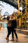 Jovem alegre e mulher abraçando e olhando uns para os outros enquanto estão dentro do pavilhão iluminado durante a data — Fotografia de Stock