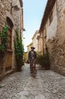 Donna in abito e cappello passeggiando per strada della città medievale — Foto stock