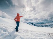 Невідома людина, що стоїть в снігу, оточена лісом і горами — стокове фото