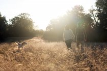 Couple avec chien à la campagne au coucher du soleil — Photo de stock