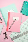 Composición de cuadernos de colores, bolígrafos, lápices, reglas y clips de papel dispuestos en escritorio rosa - foto de stock