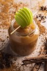Decorated with green apple appetizing juicy applesauce in glass jar and cinnamon on wooden background — Stock Photo