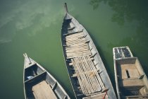 From above of row of aged traditional boats floating on peaceful green water in sunlight, Thailand — Stock Photo