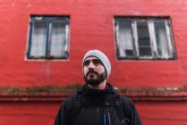 Бородатый человек смотрит в сторону, стоя перед красным зданием на Фарерском острове — стоковое фото