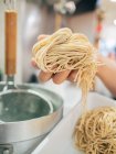 Hand of man taking noodles from tray in restaurant — Stock Photo