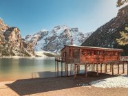 Bela paisagem com casa de madeira stilt no lago de tirar o fôlego cercado por montanhas nevadas rochosas — Fotografia de Stock