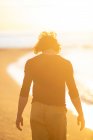 Продуманий молодий чоловік ходить на піщаному пляжі ввечері на заході сонця — стокове фото