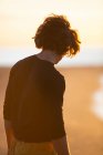 Thoughtful young man walking on the sand beach in sunset evening — Stock Photo