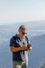 Старший использует свой мобильный телефон в горах — стоковое фото