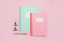 Composición de cuadernos de colores, pluma y arreglado en escritorio rosa - foto de stock