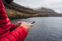 Anonymer Mann benutzt Smartphone in der Nähe eines Sees auf den Färöern — Stockfoto