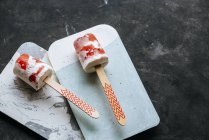 Deux popsicles pastèque et crème sur des planches sur fond sombre — Photo de stock