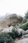 Маленький любопытный паренек в пальто спускается по скалистой склоне холма, исследует природу. — стоковое фото