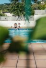 Grupo de amigos tomando banho de sol na piscina enquanto bebe cerveja em um dia de verão — Fotografia de Stock
