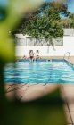 Gruppe von Freunden sonnt sich am Pool, während sie an einem Sommertag Bier trinken — Stockfoto