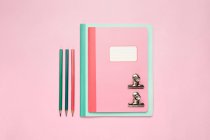 Композиція з барвистих блокнотів, олівців і розкладена на рожевому столі — стокове фото