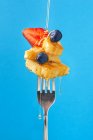 Склад солодкого десерту з полуницею та чорницею, приправлений медом на синьому фоні — стокове фото