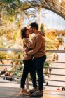 Веселий молодий чоловік і жінка приймають і цілуються, дивлячись один на одного, стоячи всередині освітленого павільйону під час побачення — стокове фото
