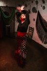 Надихнула жінку-танцюриста в яскравій спідниці фламенко, виконуючи танцювальну позицію в етнічній кімнаті з антикварними предметами на стіні — стокове фото