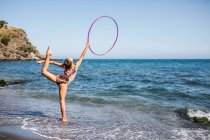 Graceful acrobat performs with hoop on beach — Stock Photo