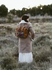 Femme en veste chaude et sac à dos tendance debout à l'extérieur en plein jour — Photo de stock