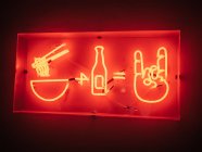 Letrero iluminado de restaurante asiático que ofrece comida y bebida colgando en la pared - foto de stock