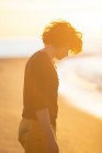 Продуманий молодий чоловік ходить на піщаному пляжі ввечері на заході сонця — стокове фото