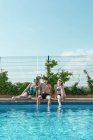 Des amis jouent avec des pistolets à eau dans la piscine par une journée ensoleillée d'été — Photo de stock