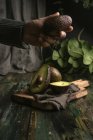 Человеческая рука держит авокадо над деревянным столом — стоковое фото