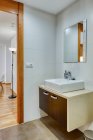 Інтер'єр ванної в мінімалістичному сучасному стилі з дзеркалом і раковиною на дерев'яній підставці — стокове фото